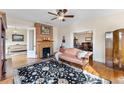 Cozy living room with hardwood floors, brick fireplace, ceiling fan, and vintage furniture at 7996 Bradburn Blvd, Westminster, CO 80030