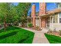 A lovely exterior view of a two-story townhome featuring brick chimney and lush green lawn and mature trees at 14093 E Radcliff Cir, Aurora, CO 80015