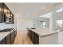Modern kitchen with stainless steel appliances, dark wood cabinets, and large island with quartz countertop at 630 Sunrise St, Erie, CO 80516