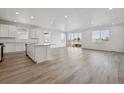 Open-concept kitchen and living room boasts abundant natural light and modern wood-look flooring throughout at 240 Lark Sparrow Way, Bennett, CO 80102