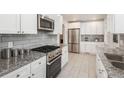 Modern kitchen featuring stainless steel appliances, granite countertops, and white cabinets at 5982 S Aberdeen St, Littleton, CO 80120