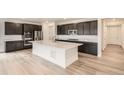 Modern kitchen with dark cabinets, stainless steel appliances, a large white island, and wood flooring at 641 Sunrise St, Erie, CO 80516