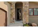 Close-up view of home's front door with stone archway, sconces, and an inviting wreath at 5149 Le Duc Ln, Castle Rock, CO 80108