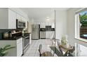 Bright kitchen with stainless steel appliances, white cabinets and a dining area with modern glass table at 1376 Ivanhoe St, Denver, CO 80220