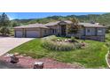 Attractive single-story home with a three-car garage, surrounded by a lush lawn and scenic mountain views at 10950 Elk Horn Run, Littleton, CO 80125