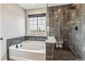 Modern bathroom featuring a soaking tub, a glass enclosed shower and stylish tile work at 6105 N Hanover St, Denver, CO 80238