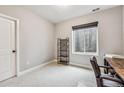 A simple carpeted bedroom features a shelving unit, window, chair, and desk at 6105 N Hanover St, Denver, CO 80238