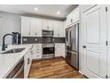 A well lit kitchen featuring stainless steel appliances, white cabinets, and dark backsplash at 6105 N Hanover St, Denver, CO 80238