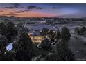 Twilight aerial view of an expansive home with beautiful landscaping and exterior lighting in a serene setting at 5603 Twilight Way, Parker, CO 80134