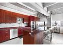 Modern kitchen features sleek red cabinets, stainless steel appliances, island and cityscape view at 100 Park W Ave # 2008, Denver, CO 80205