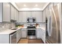 Modern kitchen with stainless steel appliances, grey cabinets, and a stylish backsplash at 2773 Roslyn St, Denver, CO 80238
