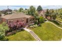 Brick home with a covered front porch, professional landscaping, and a well-maintained lawn at 5044 W Moncrieff Pl, Denver, CO 80212