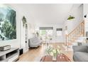 Spacious living room showcasing light wood floors, a large window, and a staircase at 4534 Nepal St, Denver, CO 80249