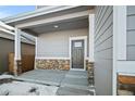 Covered front porch with stone accents and a gray front door at 774 Anderson St, Lochbuie, CO 80603