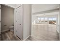 Bright living room with hardwood floors, large windows, and a view into the half bathroom at 774 Anderson St, Lochbuie, CO 80603