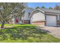 Home exterior with green lawn, mature trees, and a quaint facade with a red front door and attached garage at 5190 S Emporia Way, Greenwood Village, CO 80111