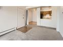 Open floor plan with carpet in the living room with an entrance door, leading to a kitchen with wood cabinets at 5995 W Hampden Ave # 23, Denver, CO 80227