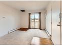 Living room with carpet, sliding glass doors to a balcony, baseboard heaters, and an air conditioning unit at 5995 W Hampden Ave # 23, Denver, CO 80227