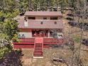 Aerial view of the exterior of the home with a large deck surrounded by dense trees at 10852 Conifer Mountain Rd, Conifer, CO 80433