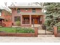 Inviting red brick home featuring a classic design, covered porch and meticulous landscaping at 925 N Emerson St, Denver, CO 80218