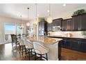 Modern kitchen featuring dark cabinets, granite counters, and a stylish island with seating at 12371 Red Fox Way, Broomfield, CO 80021