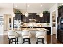 Elegant kitchen with dark cabinets, granite countertops, island seating and pendant lighting at 12371 Red Fox Way, Broomfield, CO 80021