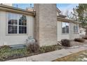 A close up of the side of the house with a well-maintained brick chimney and clean vinyl siding at 2062 S Xenia Way, Denver, CO 80231