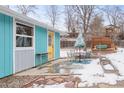 Backyard patio with table, chairs, and garden beds visible outside a light blue house with a yellow door at 457 Verdant Cir, Longmont, CO 80504