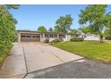 Exterior view of a home with a long driveway, well-kept lawn, and mature trees at 845 Everett St, Lakewood, CO 80215