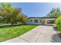 Well-maintained home features a long driveway, covered parking, and a lush front yard at 1570 S Chase St, Lakewood, CO 80232