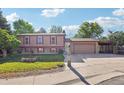 Traditional home with a well-kept lawn, brick accents, and a large driveway leading to an attached garage at 11112 Dahlia Way, Thornton, CO 80233