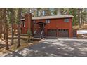 A charming wood home with an attached garage, complemented by lush trees and a paved driveway at 28630 Pine Dr, Evergreen, CO 80439