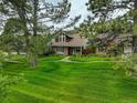 Well-kept two-story home with brick and shingle exterior and a spacious lawn with mature trees at 7409 E Jamison Dr, Centennial, CO 80112