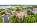 Stunning aerial view of home, showcasing lush landscaping, tile roof, and lake view at 14154 Lexington Cir, Westminster, CO 80023