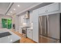 Modern kitchen boasts stainless steel appliances, white cabinets, and a view of the cozy living room at 2831 W 25Th Ave # 3, Denver, CO 80211