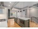 Spacious kitchen island with stainless steel microwave and sink, pendant lights, and hardwood floors at 2831 W 25Th Ave # 3, Denver, CO 80211