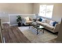 Bright living room with wood floors, a large window, and modern furniture at 6147 Dunraven, Golden, CO 80403