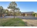 Charming single-story home with a three car garage, stone accents, and a well-manicured lawn at 3842 Estates Cir, Larkspur, CO 80118