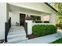 Inviting front porch with white brick columns, black railings, a dark wood door, and decorative potted plants at 474 S Vine St, Denver, CO 80209