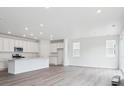 Bright, open kitchen with white cabinets, stainless steel appliances, and wood-look floors at 45922 Gentry Ave, Bennett, CO 80102