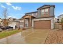 A two-story home featuring stone accents, a front yard, and an attached garage at 1820 Ghost Dance Cir, Castle Rock, CO 80108