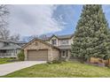 Charming two-story home boasts a stone-accented garage, lush lawn, and mature tree at 2420 S Ellis Ct, Lakewood, CO 80228