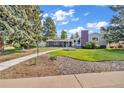 Landscaped front yard with decorative rocks, healthy lawn, and a paved walkway leading to the home at 1830 Zang St, Golden, CO 80401