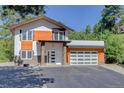 Modern home featuring a spacious driveway, stone accents, and a contemporary garage door at 1688 Pine Valley Rd, Evergreen, CO 80439