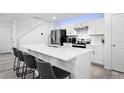 Bright kitchen boasts white cabinetry, stainless steel appliances, sleek countertops, and bar stool seating at 28330 E 6Th Pl, Watkins, CO 80137