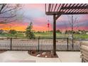Enjoy the outdoor sunset from this serene patio overlooking a lush green landscape, complete with a pergola and black iron fence at 10061 Bluffmont Ct, Lone Tree, CO 80124