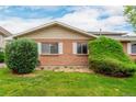 Charming brick townhome exterior features green bushes, a well-maintained lawn, and bright white window shutters at 9824 Lane St, Thornton, CO 80260