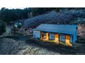 Well-maintained barn with stalls, lit up at night with horses in the landscape at 20951 Pleasant Park Rd, Conifer, CO 80433