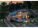 A beautiful exterior view of the house featuring a deck and lovely landscaping at 20951 Pleasant Park Rd, Conifer, CO 80433