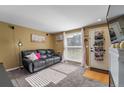 A comfortable living room with cozy carpet, a black leather couch, and bright natural light at 5809 S Pearl St, Centennial, CO 80121